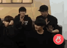 a group of young men are sitting on a couch and clapping their hands