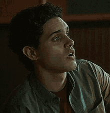 a close up of a man wearing a denim shirt and a red shirt making a funny face .