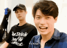 two young men are sitting next to each other and one of them is wearing a t-shirt that says be drink and we come