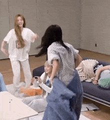 a group of women are playing with pillows in a living room .