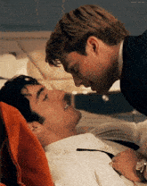 a man in a suit and tie is kissing another man on the forehead
