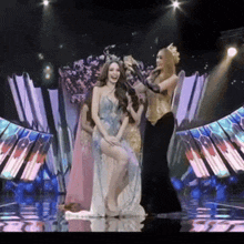 a woman in a blue dress is sitting on a stage with other women