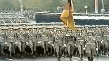 a group of soldiers marching in a parade with a yellow flag