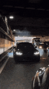a black car is driving through a tunnel with smoke coming out of the tires