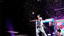 a man singing into a microphone on a stage with confetti falling