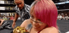 a woman with pink hair is wrestling a man in a ring .