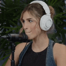 a woman wearing white headphones is making a face in front of a microphone