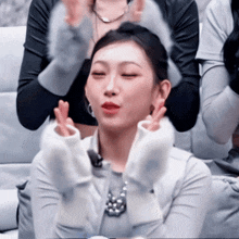 a woman with her eyes closed is making a peace sign