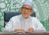 a man wearing glasses and a white shirt is sitting at a table with a book