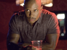 a bald man is sitting at a bar holding a plastic cup