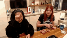 two women sitting at a table with one wearing a shirt that says jack daniels on it