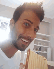 a man with a beard is smiling while holding a slice of cake