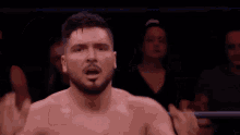 a man with a beard is standing in a wrestling ring with his hands in the air .