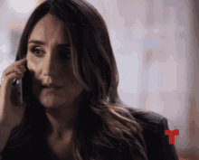a woman talking on a cell phone with a red t on the bottom