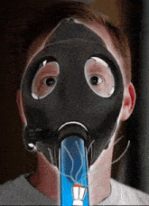 a man wearing a gas mask is smoking a blue bong