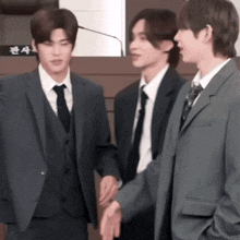 three young men in suits and ties are standing next to each other .