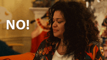 a woman with curly hair is sitting in front of a sign that says " no "