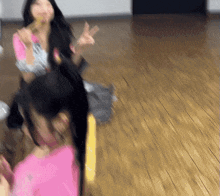 a woman in a pink shirt is sitting on a wooden floor