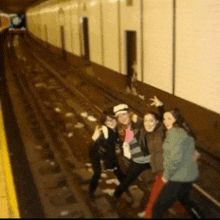 a group of women are posing for a picture on the tracks of a train