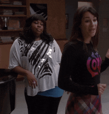 two women are standing next to each other and one is wearing a shirt with the letter o on it