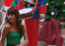 a woman in a green elf costume is dancing in front of a nutcracker
