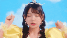 a girl wearing a yellow dress and a pearl tiara