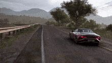 a red sports car is driving down a road with mountains in the background and a license plate which says a420