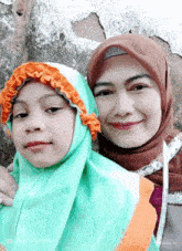 a woman and a little girl are posing for a picture and the girl is wearing a green head scarf