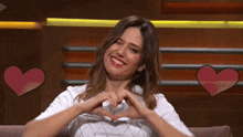 a woman making a heart shape with her hands in front of two hearts