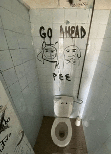 a bathroom with graffiti on the wall including go ahead pee