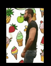 a man with a beard is standing in front of a pattern of ice cream cones and fruit .