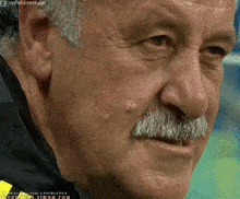a close up of a man 's face with a mustache and a watermark that says ' soccer ' on it