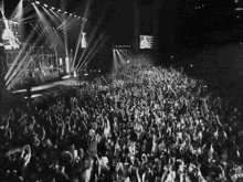 a black and white photo of a crowd at a concert with their hands in the air