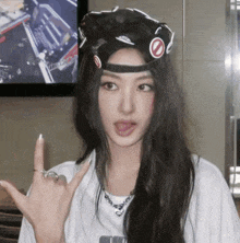 a woman wearing a black hat and a white shirt is making a rock sign