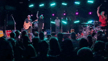 a man in a hat is singing into a microphone while playing a guitar in front of a crowd of people .