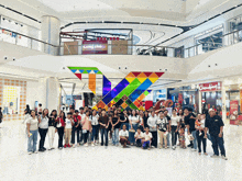 a group of people are posing for a picture in a shopping mall with a world balance sign in the background
