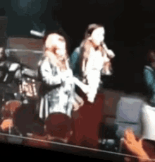 a blurry picture of two women singing into microphones
