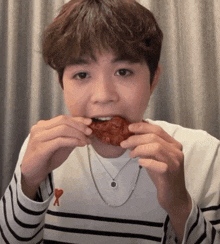 a man wearing a striped shirt with a heart on it is eating a piece of food