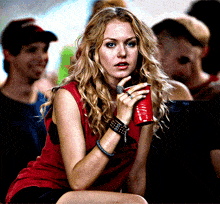 a woman in a red tank top is holding a red cup in her hand