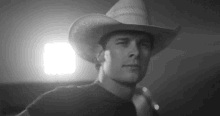 a man wearing a cowboy hat is standing in front of a light .