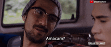a man with glasses and a beard is talking to another man with the words " amacam " written on the bottom