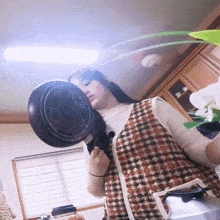 a woman holds a frying pan over her head in a kitchen