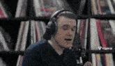 a man wearing headphones and a hat is singing into a microphone .