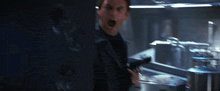 a man in a black suit is holding a gun with his mouth open