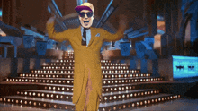 a man in a yellow suit stands on a stage