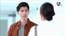 a man in a brown shirt is standing next to a woman in a white shirt .