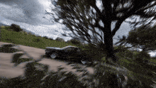a car is driving down a road with a tree in the background