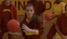 a girl in a red shirt is dancing in front of a group of people .