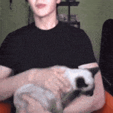 a man in a black shirt is petting a cat