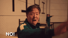 a man in a green jacket says no in front of a brick wall